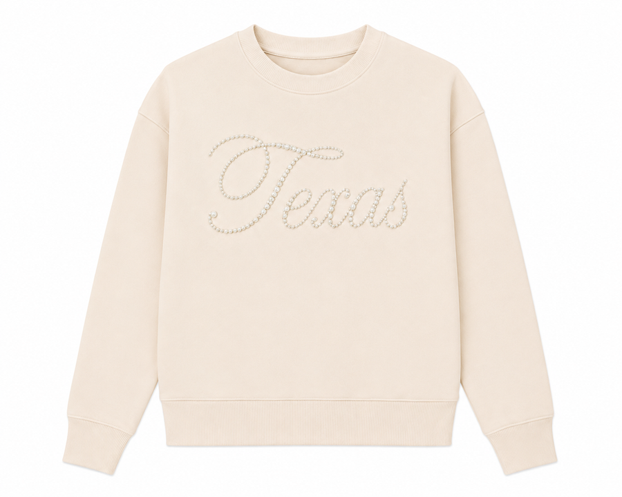 Front view of the Ashley Herrera Texas Pearl Sweatshirt in cream featuring elegant pearl "Texas" script, a relaxed silhouette, ultra-soft premium fabric, and three gold-tone golf tee holders on the sleeve.