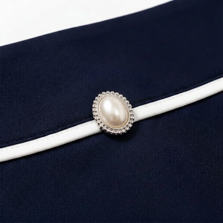 Close-up of the oval pearl embellishment and white waist piping on the navy Monroe skirt